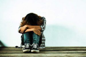 Mujer con la cabeza entre sus rodillas por problema de sorderaque trata Pallarés centro auditivo en Orihuela