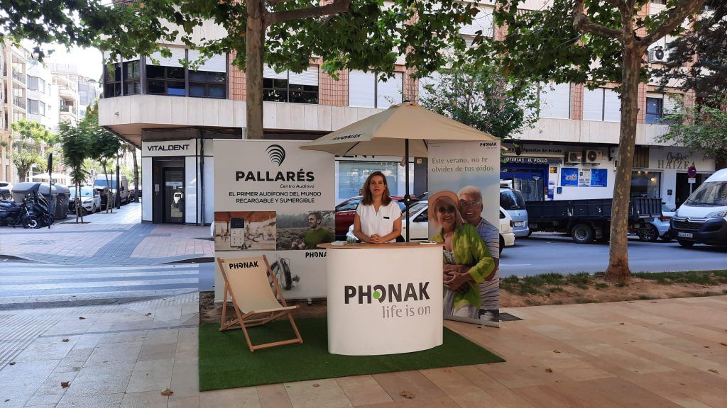Stand de una campaña de Phonak para la prevención de la pérdida auditiva en Orihuela con personal de Pallarés Centro Auditivo en una calle de Orihuela